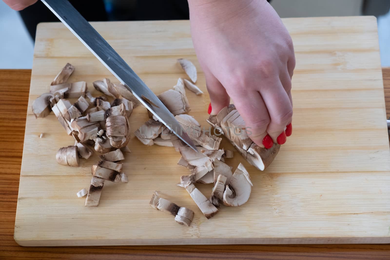 Woman cutting mushrooms on wooden board