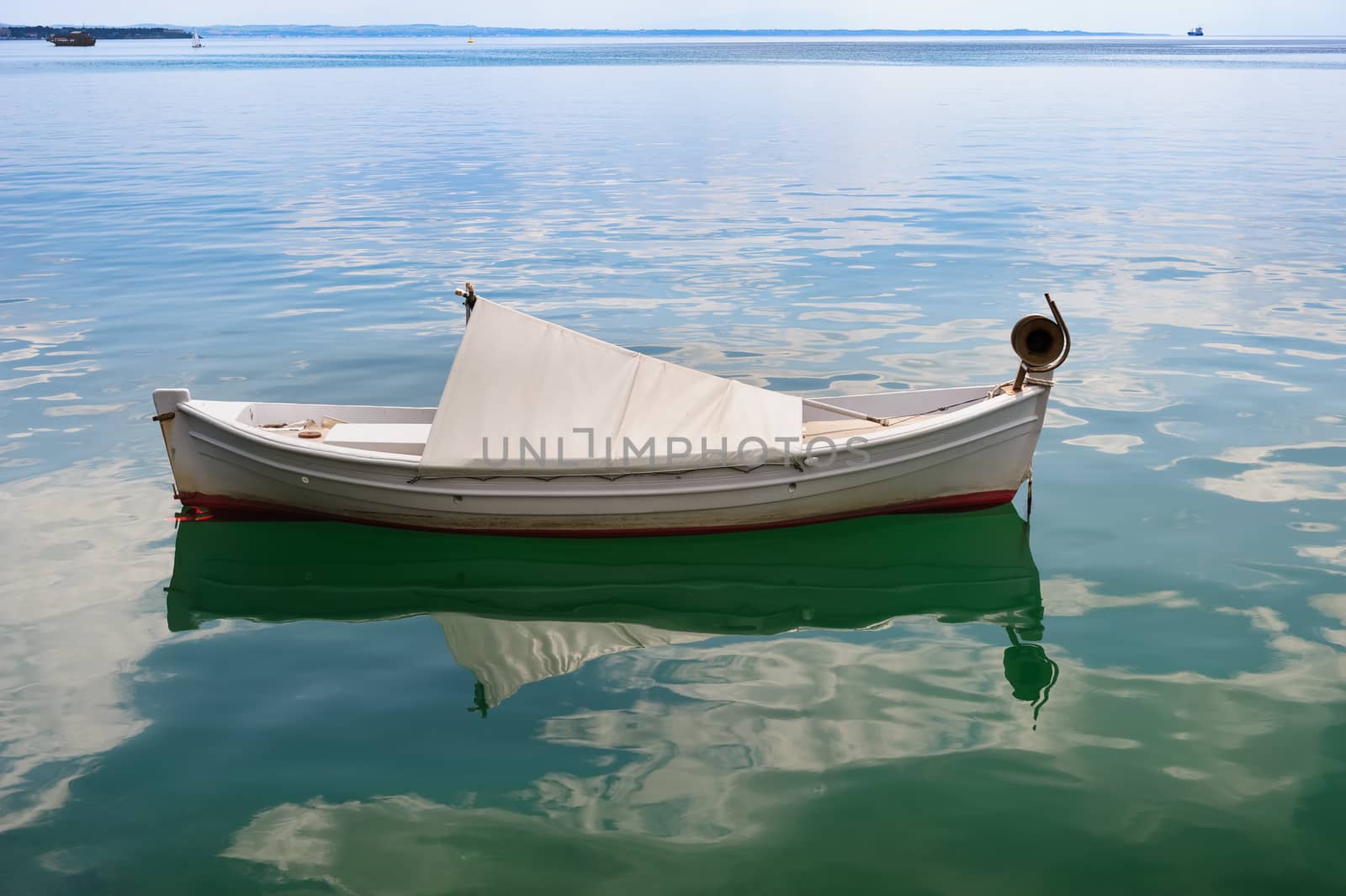 Very small white fishing boat at sea surface