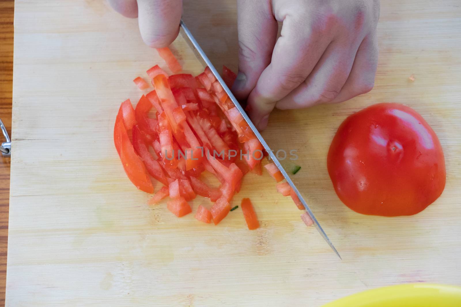 cooking, food and home concept - close up of male hand cutting tomato on cutting board at home by rdv27