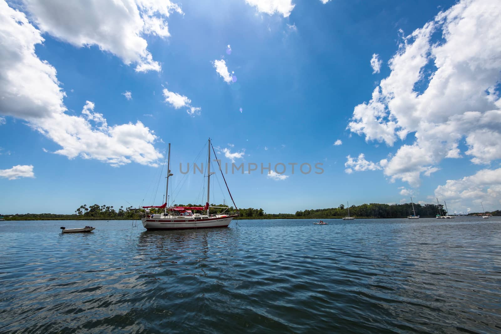 A sail boat on a lake with island behind