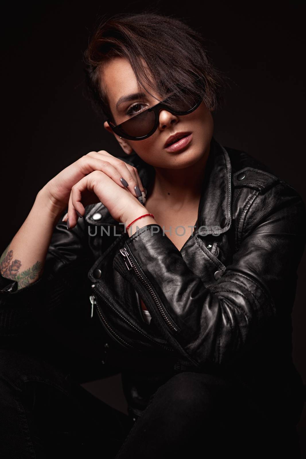 Beauty sexy woman in a leather jacket. Portrait on a dark background