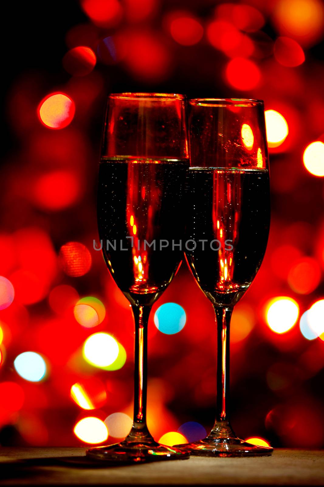 Two champagne glasses on color bokeh background