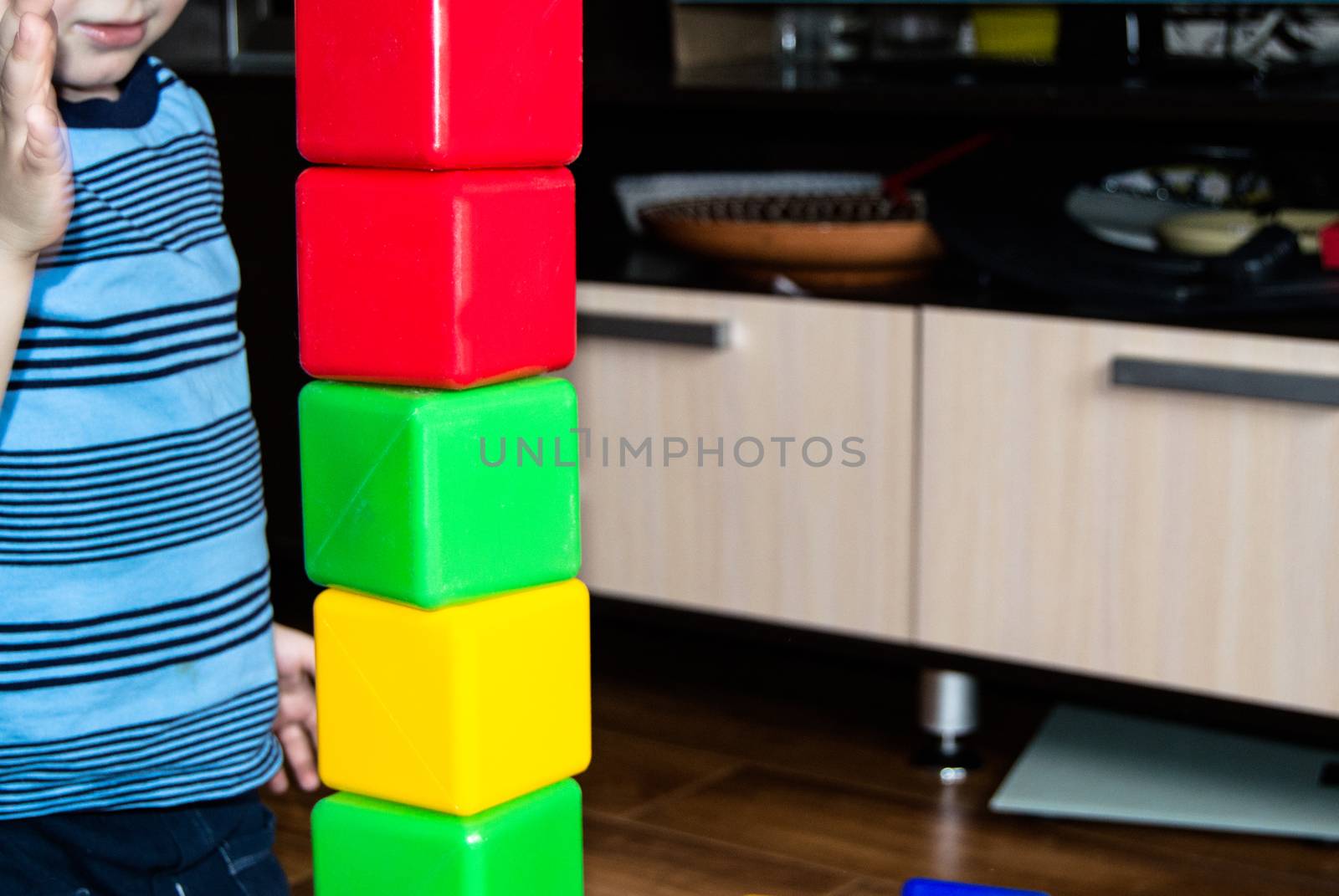 A small child playing with colorful cubes builds a tower, the concept of early education preparation for the development of the school by claire_lucia