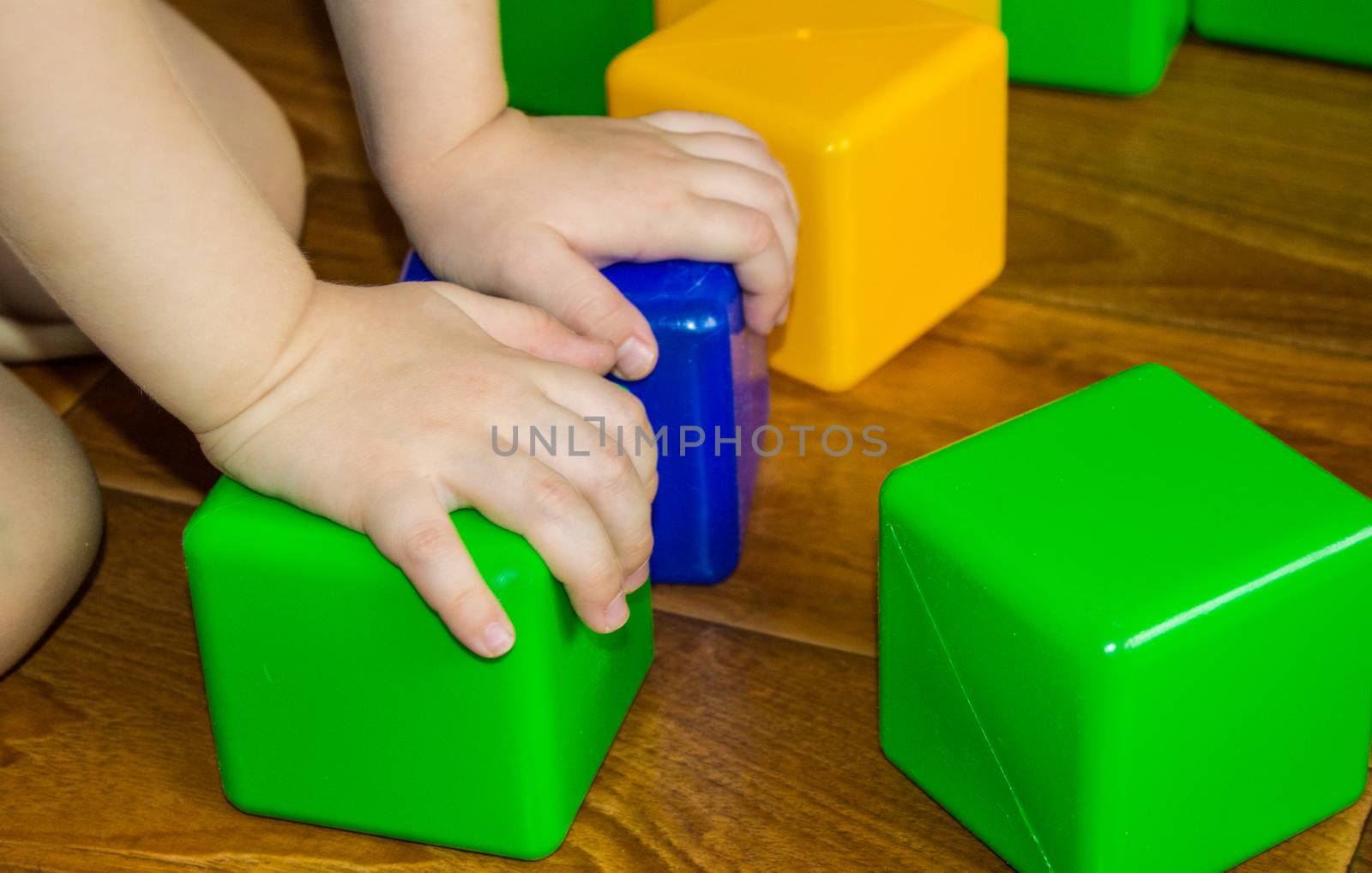 A small child playing with colorful cubes builds a tower, the concept of early education preparation for the development of the school.