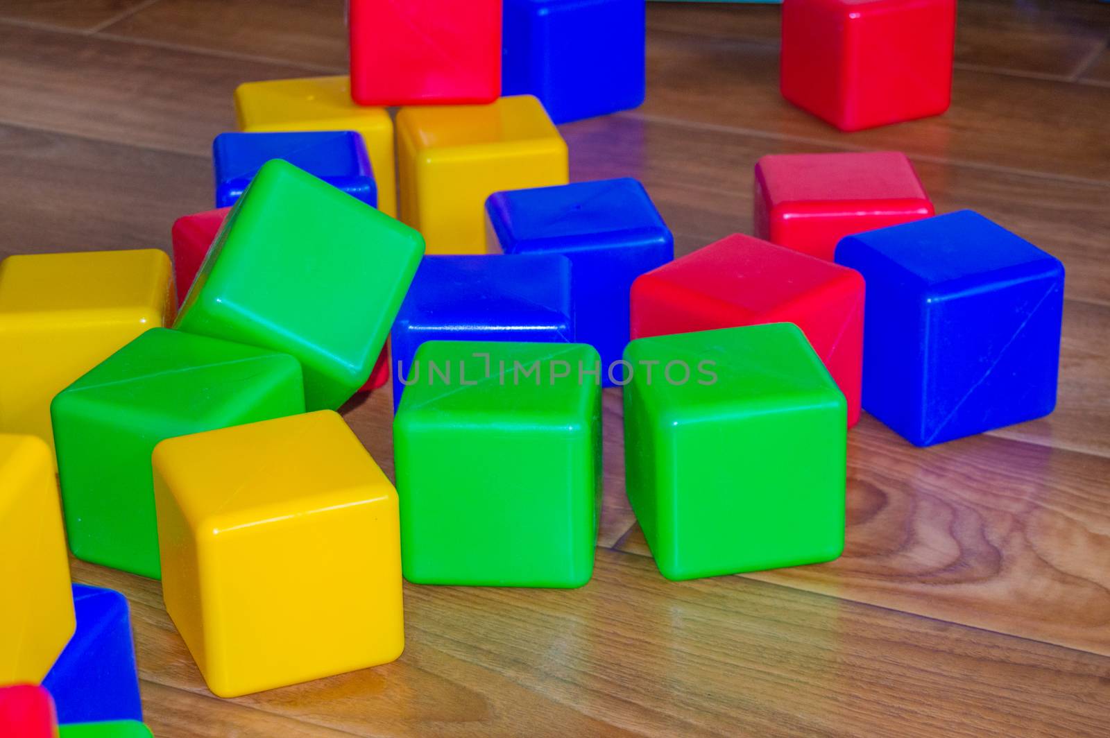 Colorful plastic cubes for children's games are scattered on the wooden floor.