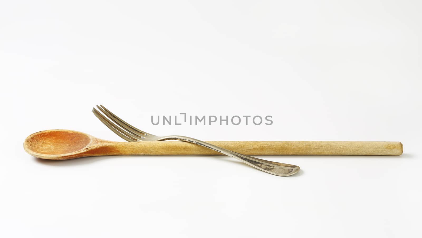 Wooden spoon and metal fork on white background