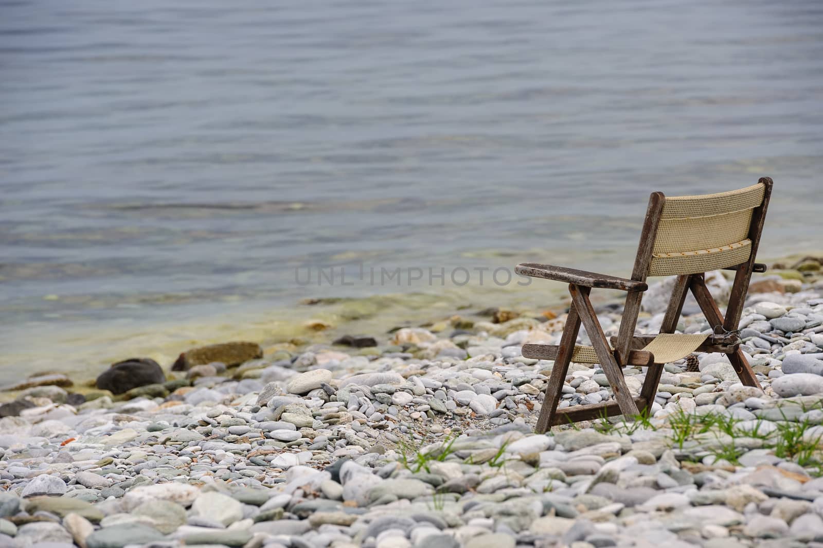 old tired wooden foldable chair at stone beach