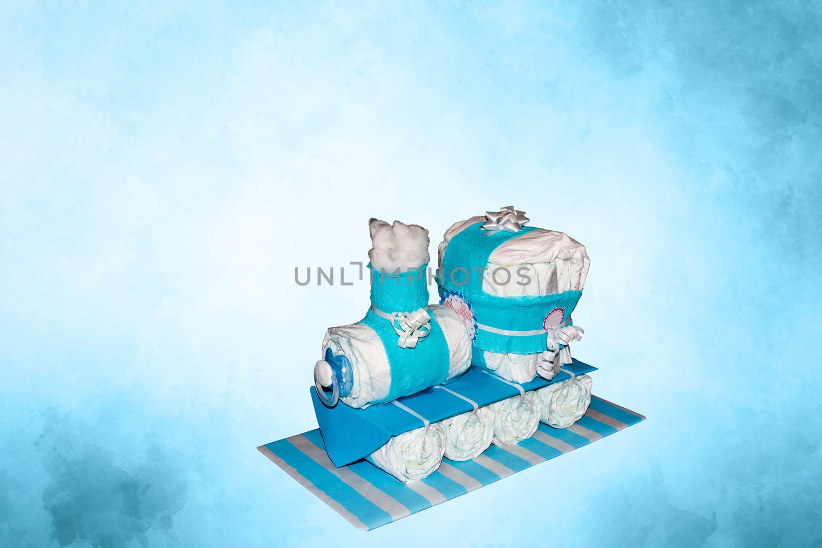 Diaper cake. A nappy pie locomotive with blue ribbons. Gift for the birth of a child