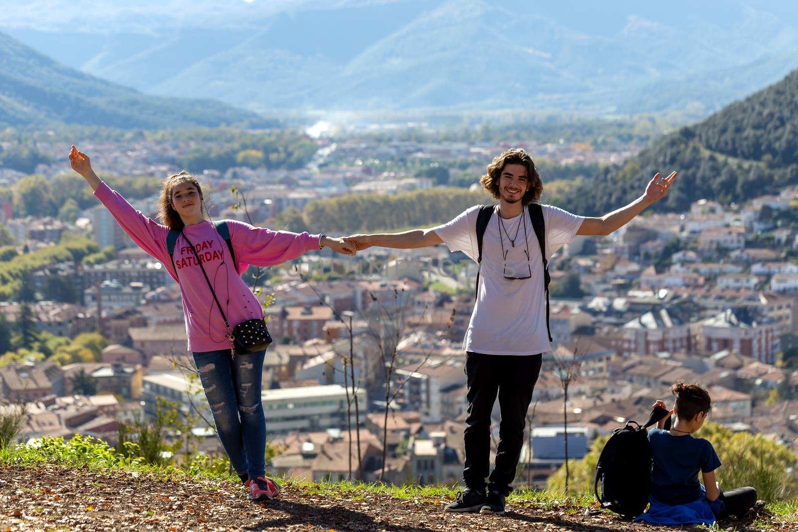 Hikers with backpacks relaxing on top of a mountain and enjoying the view of valley by Anelik