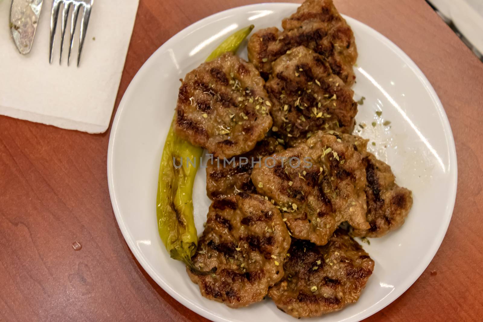 an upper view shoot to meat and some fried pepper. this food photo has taken at a restaurant.