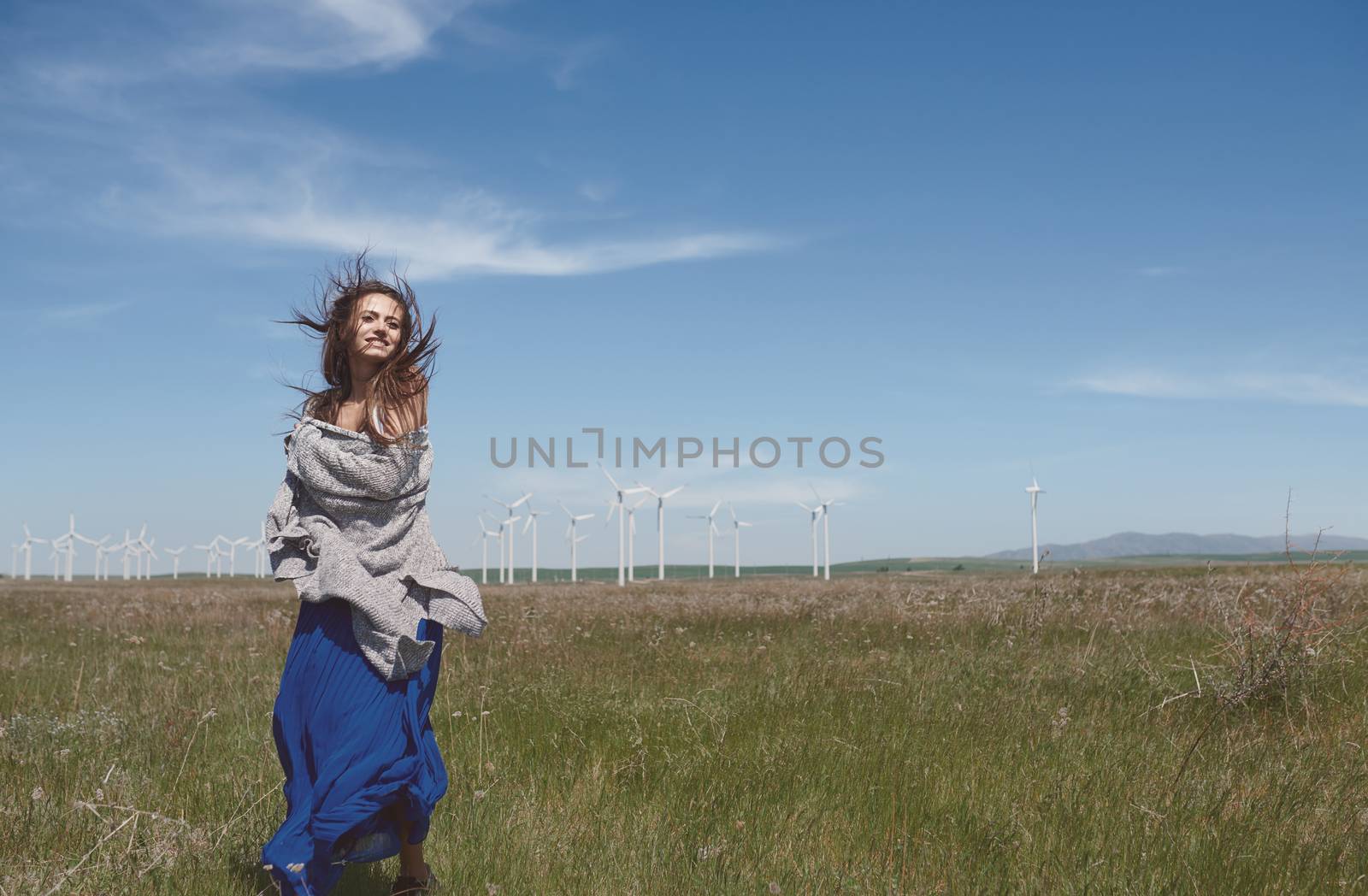 Woman with long tousled hair next to the wind turbine with the w by Novic