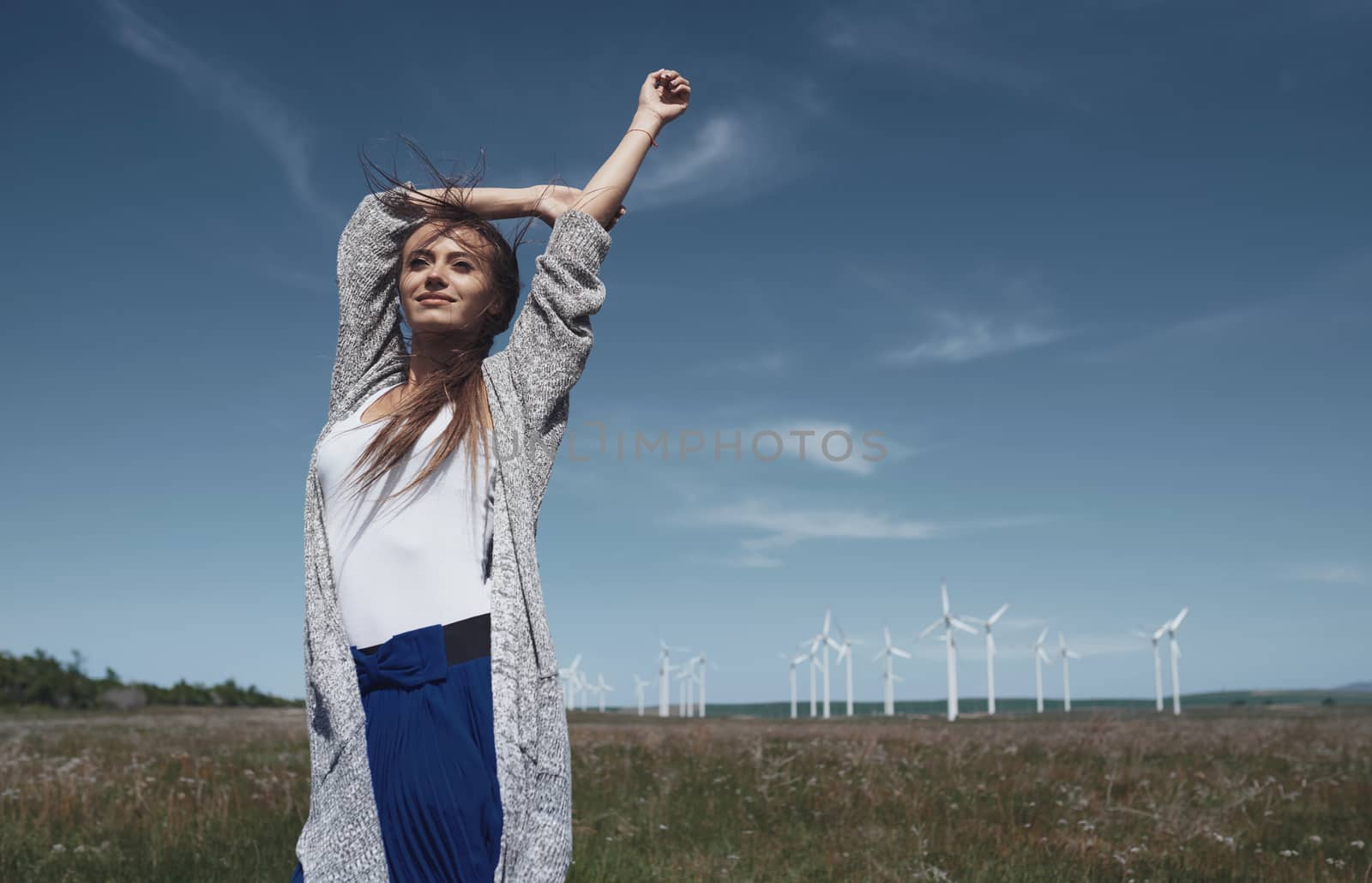 Woman with long tousled hair next to the wind turbine with the w by Novic