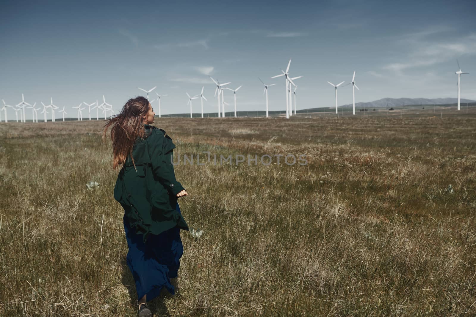 Woman with long tousled hair next to the wind turbine with the w by Novic