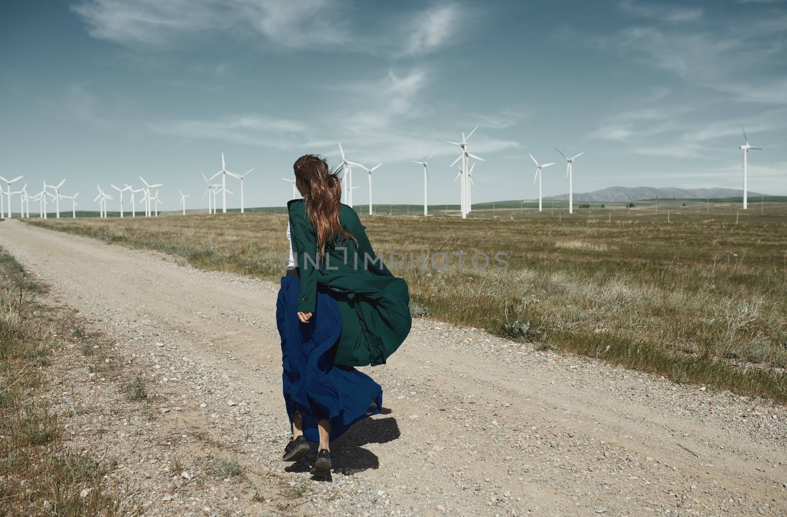 Woman with long tousled hair next to the wind turbine with the wind blowing