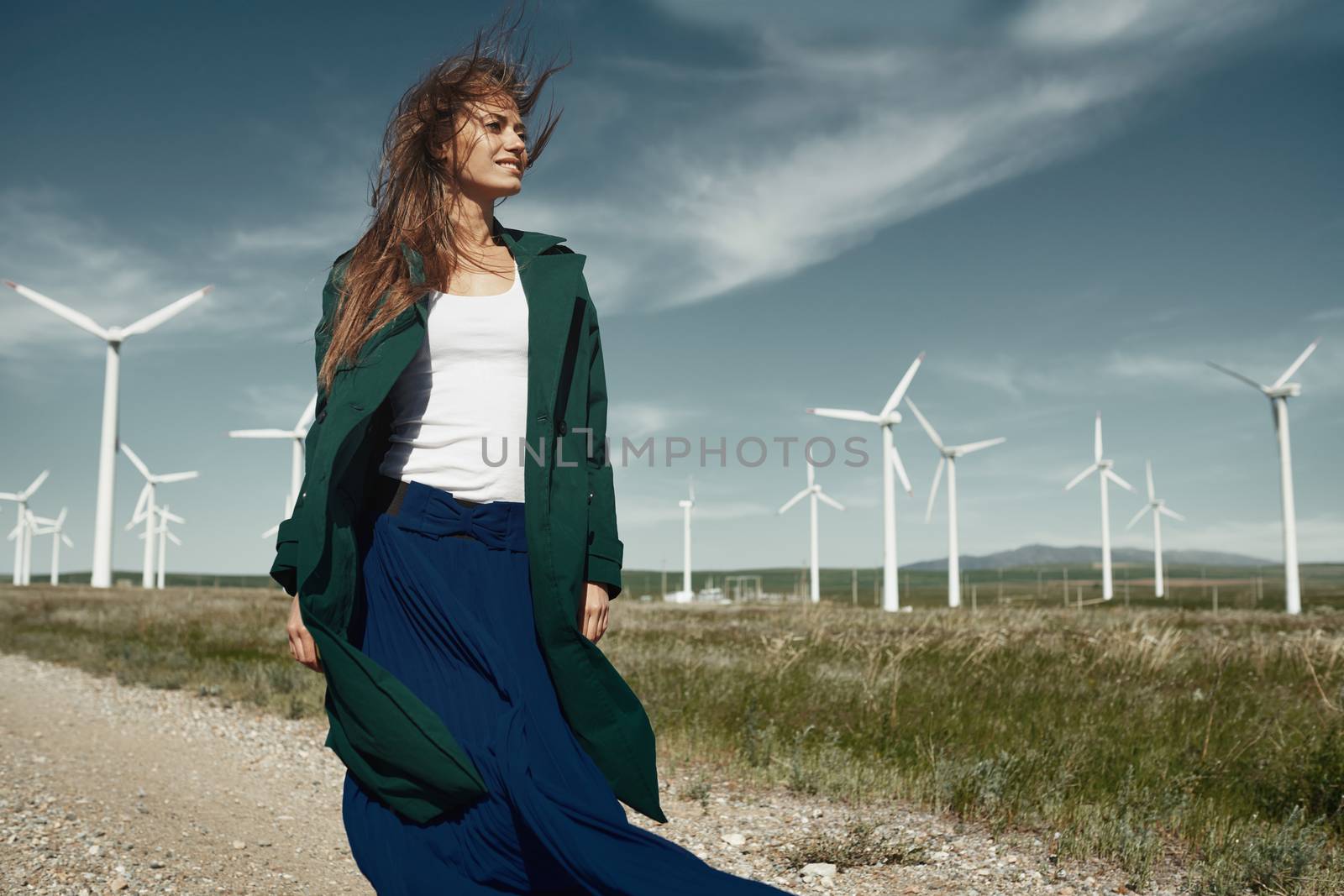 Woman with long tousled hair next to the wind turbine with the wind blowing