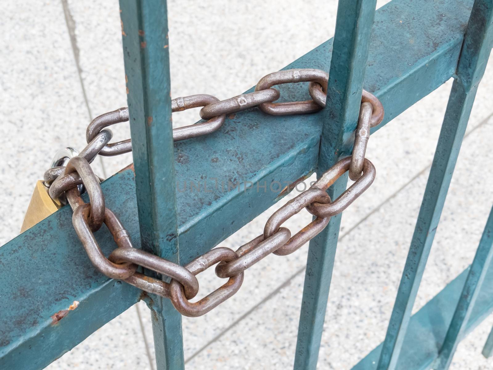 Rusted padlock and chain, in blue grid, to close gate.