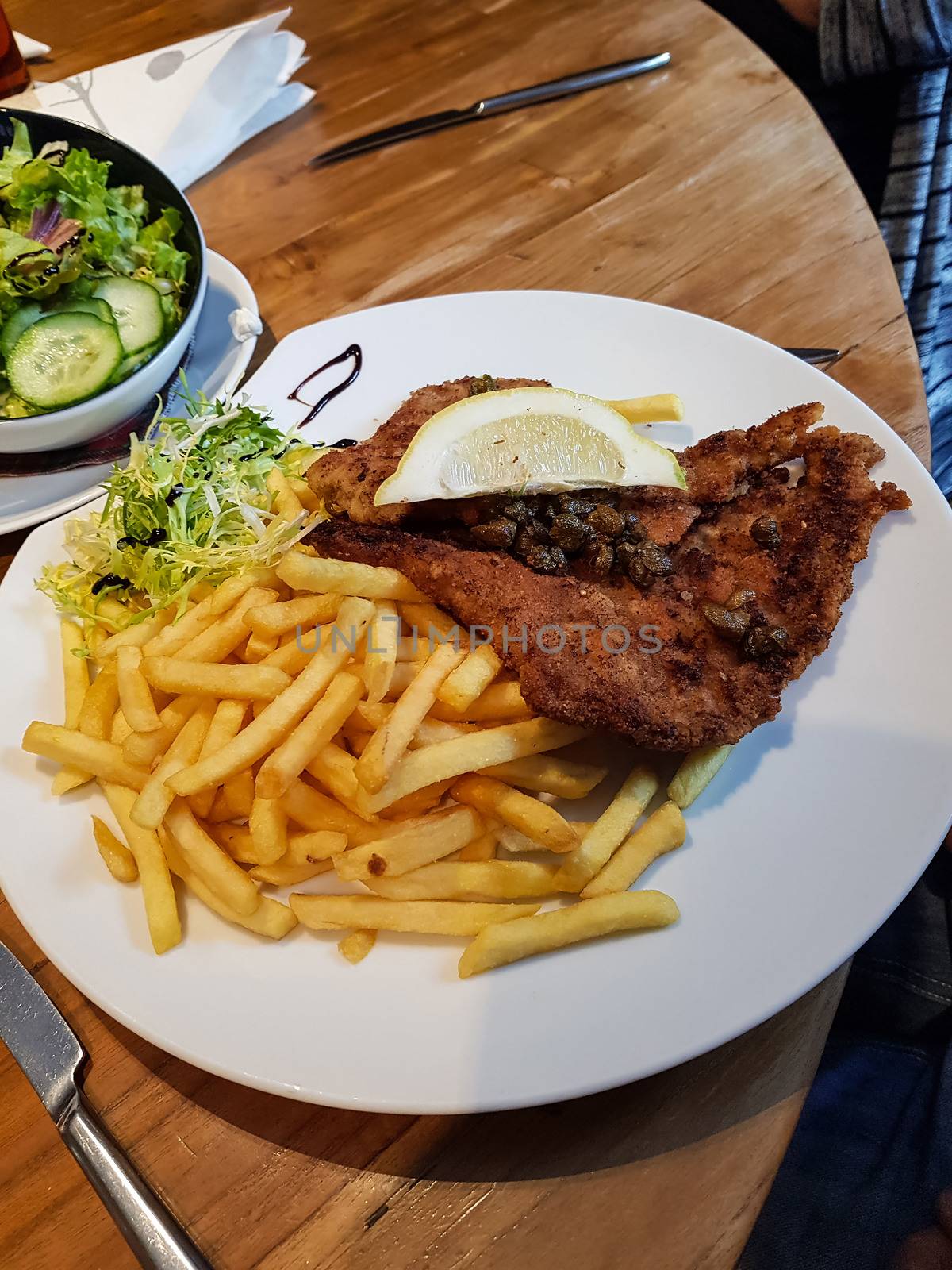 Chicken schnitzel served with french fries and salad. Natural wood background. front view