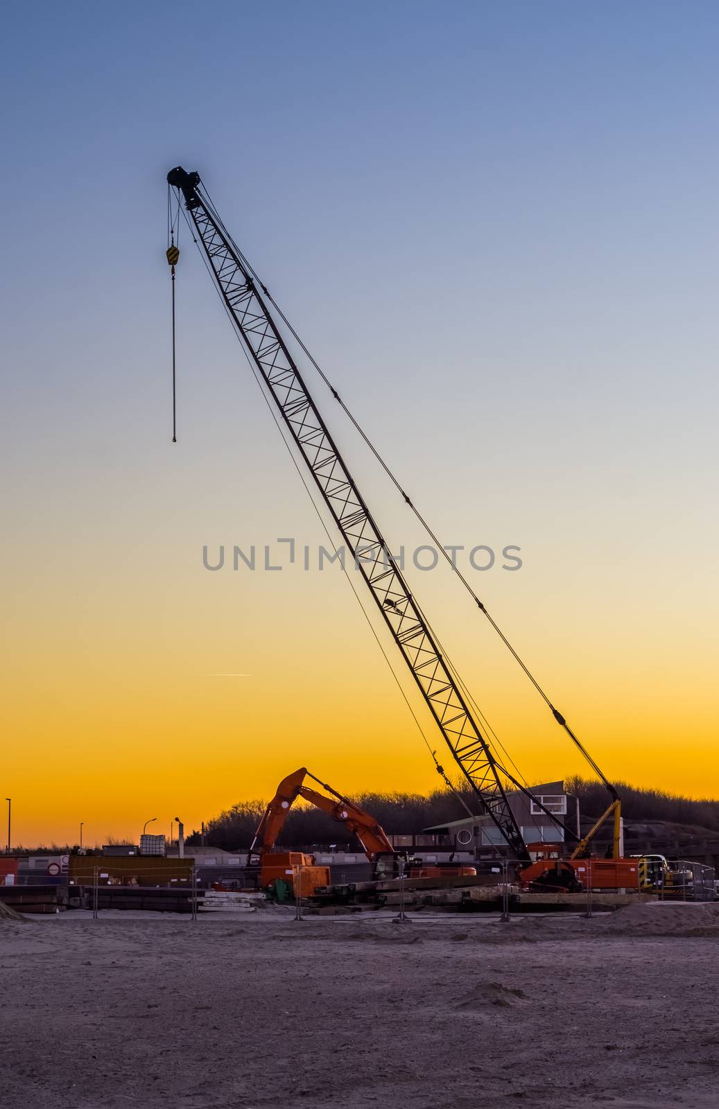 large construction crane with excavators at the beach during sunset, construction site at the beach