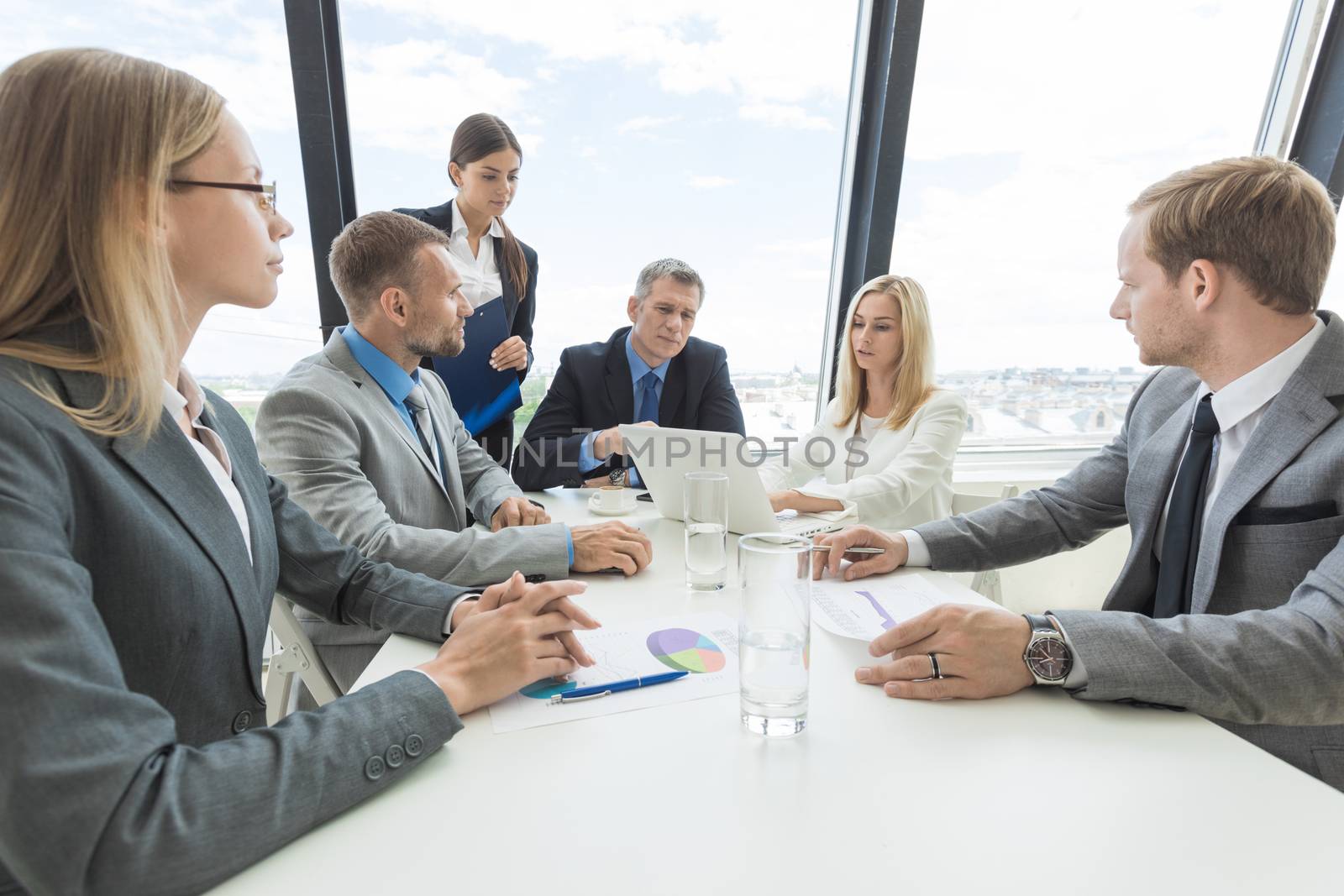 Mixed group of white collar workers at business meeting discuss documents