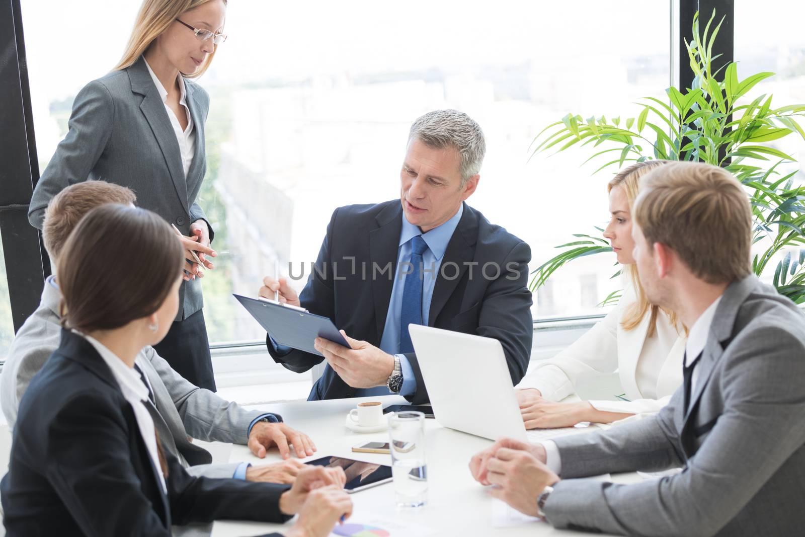 Mixed group of white collar workers at business meeting discuss documents, Business man reading contract at office table