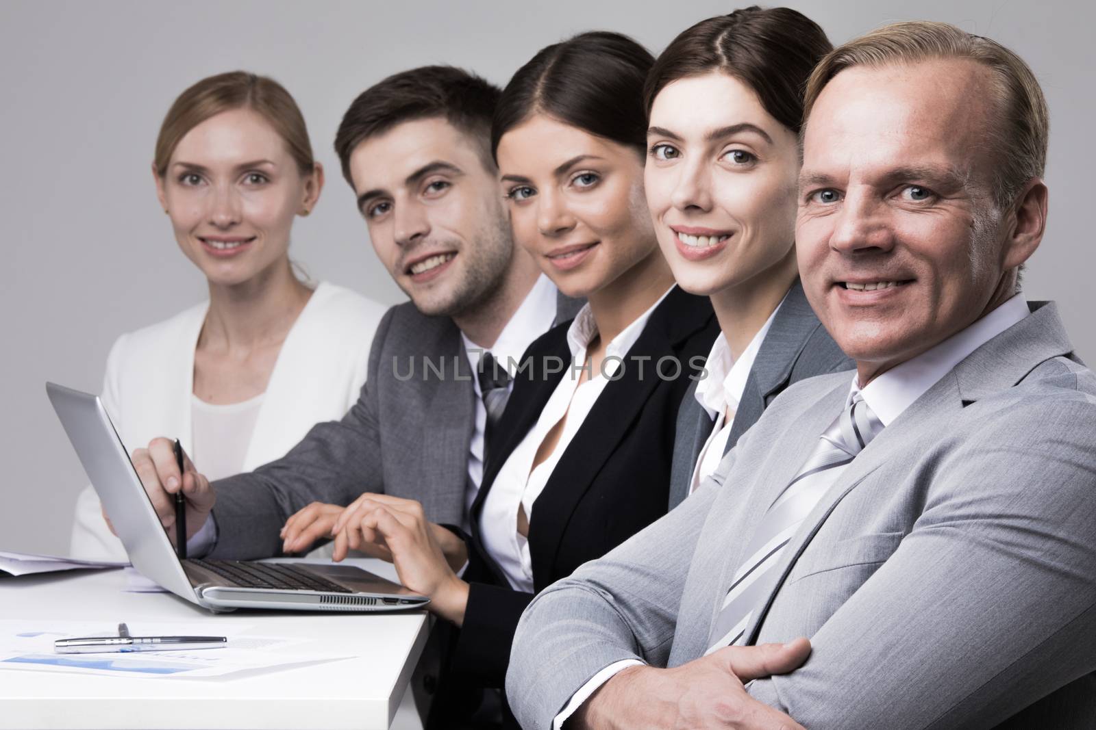 Business people sitting in a row and working together with laptop and documents