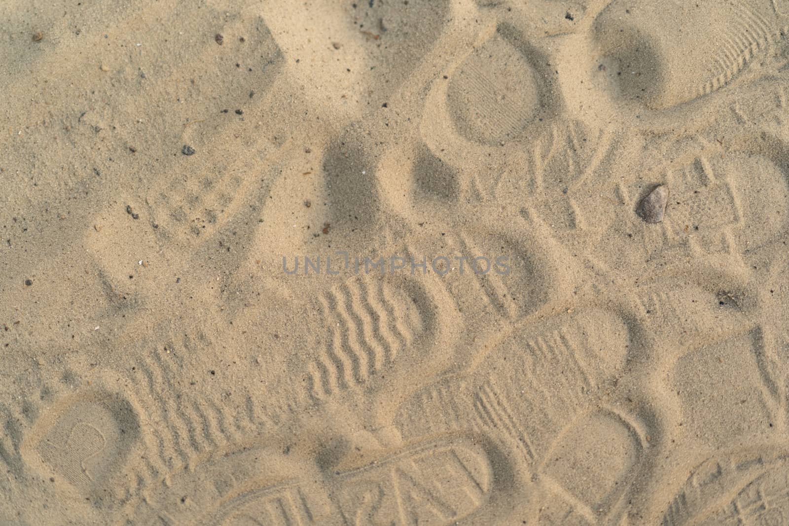 Sand on the beach with footprints and shoes. Many footprints with shoes and without shoes.