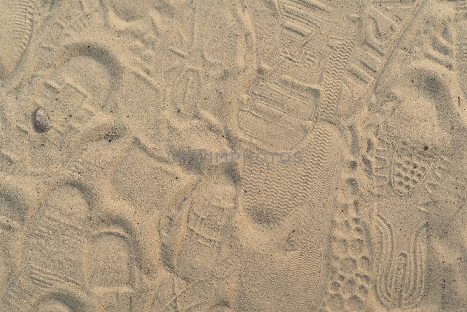 Sand on the beach with footprints and shoes. Many footprints with shoes and without shoes.