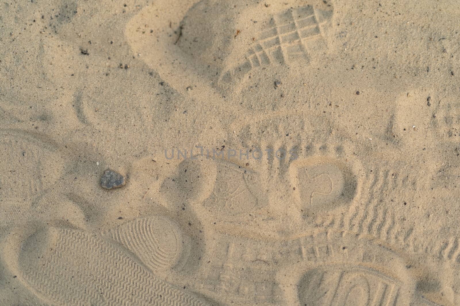 Sand on the beach with footprints and shoes. Many footprints with shoes and without shoes. by alexsdriver