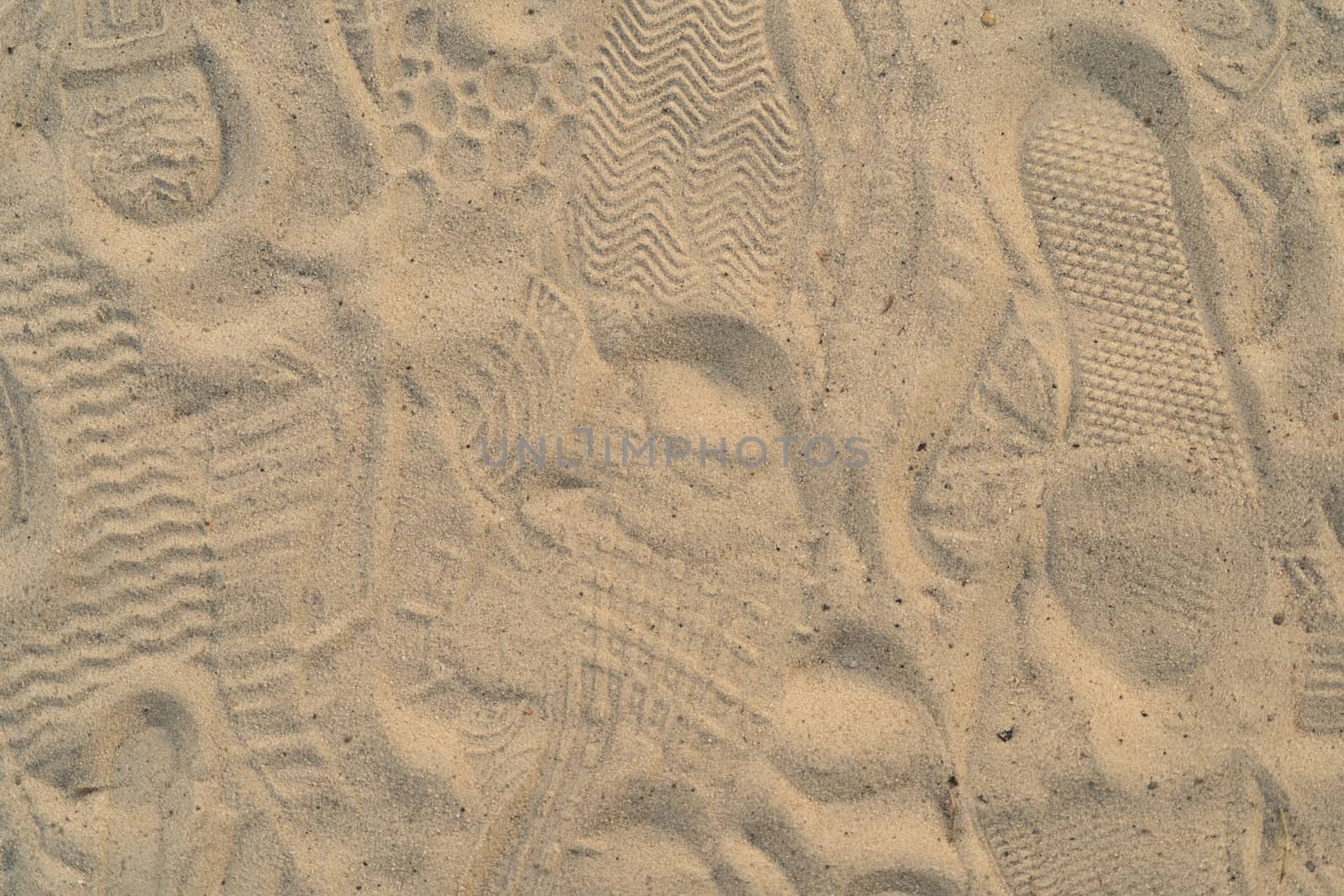 Sand on the beach with footprints and shoes. Many footprints with shoes and without shoes.