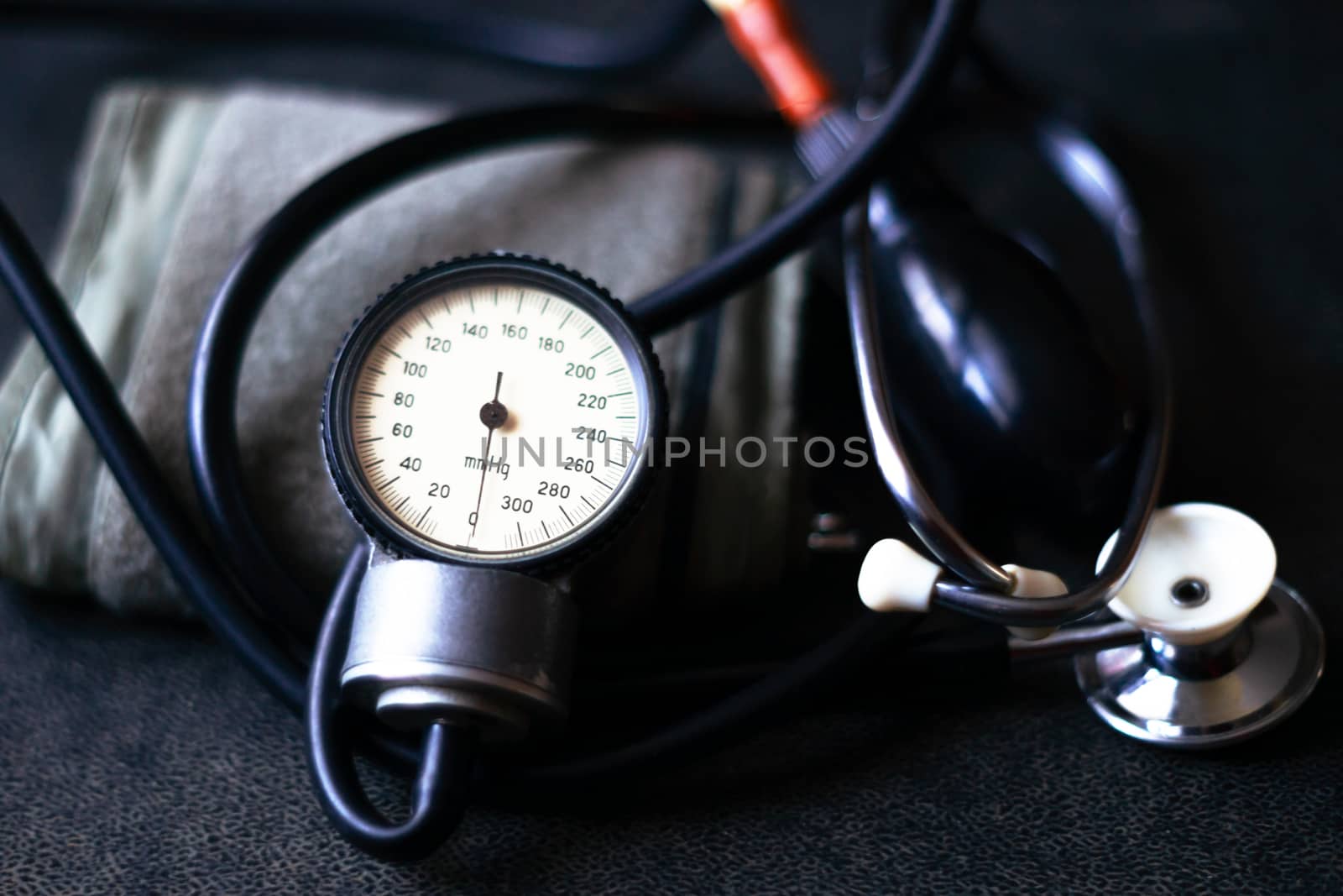 Analog tonometer with cuff and phonendoscope on old suitcase. Close up view and blurred background. Underexposed photo.