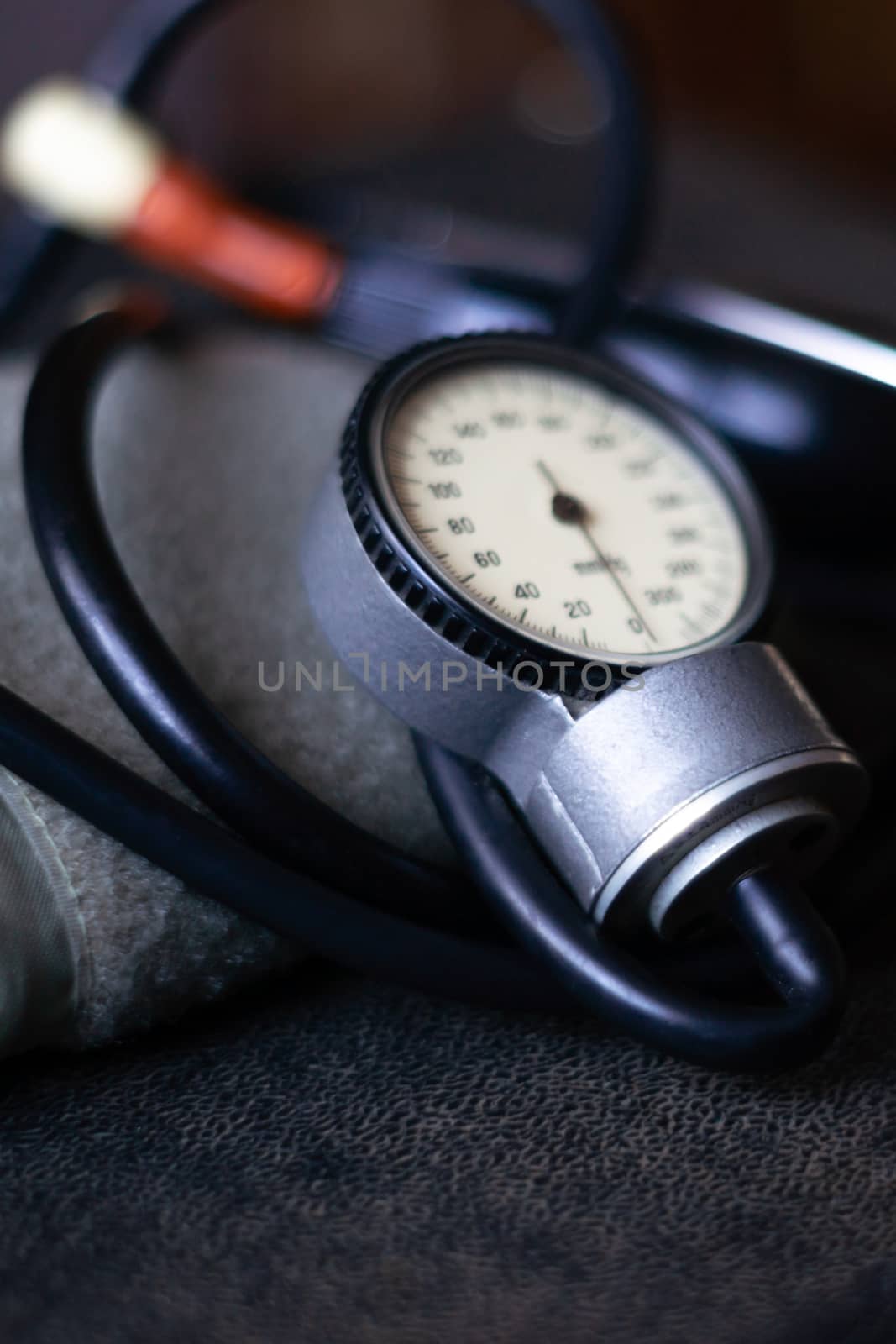 Analog tonometer with cuff and phonendoscope on old suitcase. Close up view and blurred background. Underexposed photo.