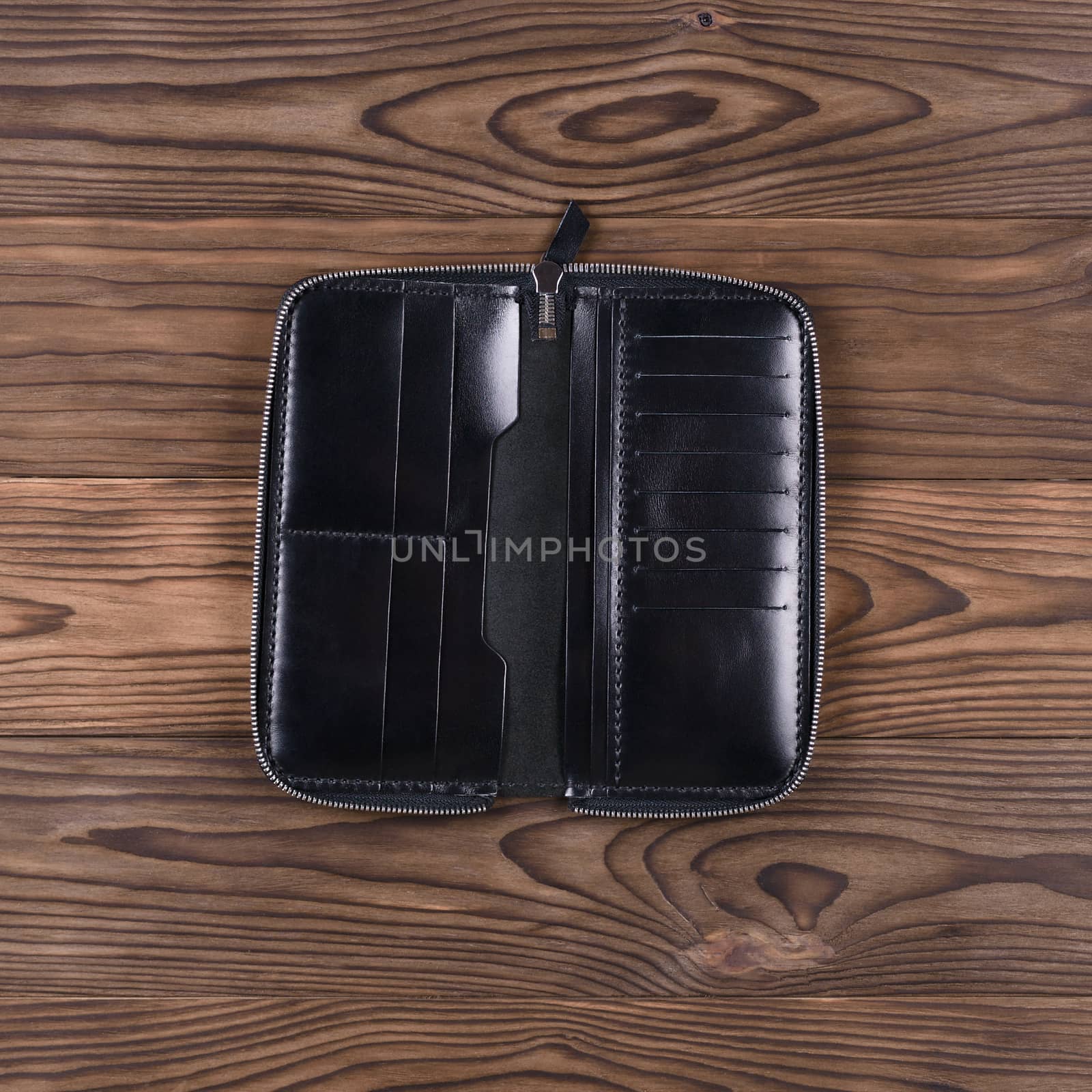Gloss black color handmade leather porte-monnaie on wooden textured background. Oper purse. Up to down view. Stock photo of luxury accessories.