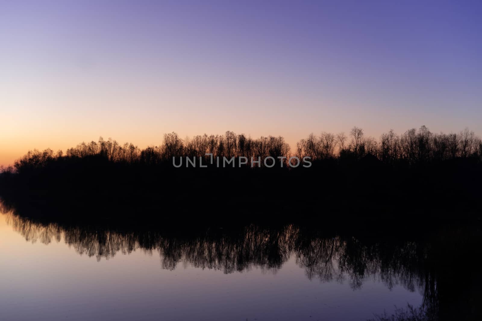 Blue time evening sky landscape with trees and lake in foreground. Blue time sunset. Perfect teal and orange colors. Low-light underexposed photo. by alexsdriver