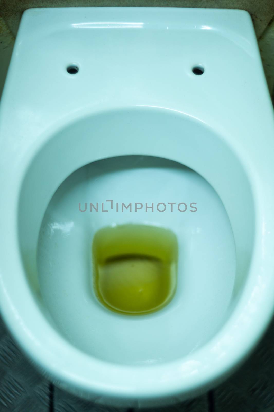 Dirty terrible toilet in a public toilet. Plating deteriorated from moisture and urine. Hue yellow urine in toilet, dirty floor.