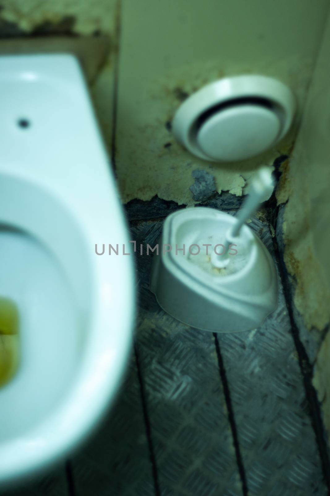 Dirty terrible toilet in a public toilet. Plating deteriorated from moisture and urine. Hue yellow urine in toilet, dirty floor.