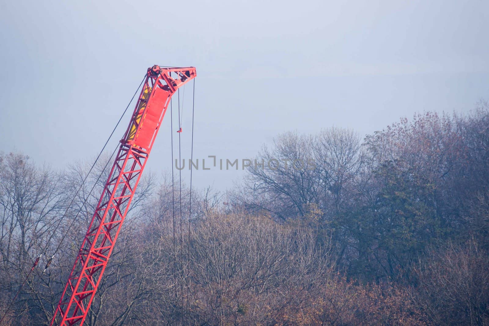 Construction process with construction automotive crane with red gibbet. Autumn fog and river bridge  on blurred background. Forest around crane. by alexsdriver