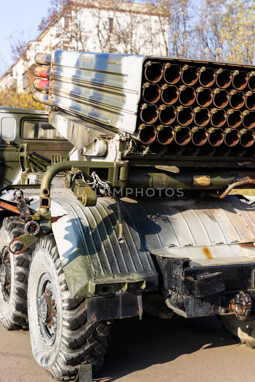 Camouflage military truck with rocket launcher. Outdoor military vehicles museum. Armor is damaged at the battlefield. Missile firing system on military armored truck close up view. Rocket launcher.