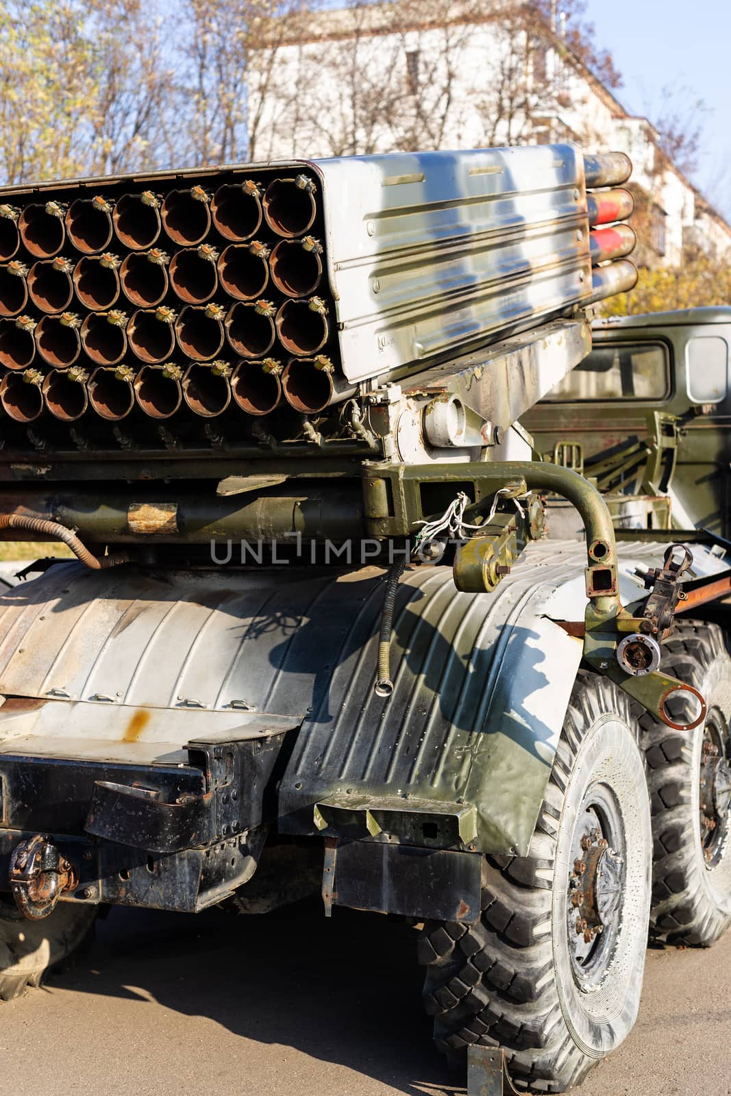 Camouflage military truck with rocket launcher. Outdoor military vehicles museum. Armor is damaged at the battlefield. Missile firing system on military armored truck close up view. Rocket launcher. by alexsdriver