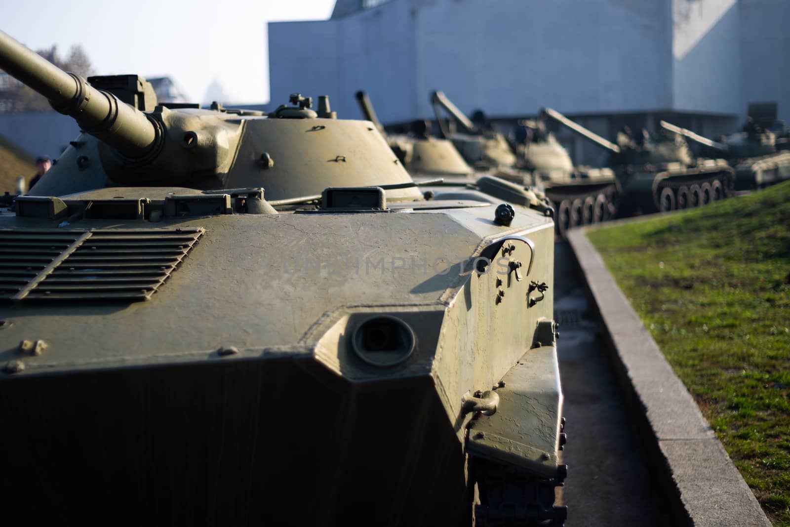 Parts of the hull of the armored infantry vehicle. In front and back of vehicle stays many different armored military vehicles. Military equipment outdoor open air museum.