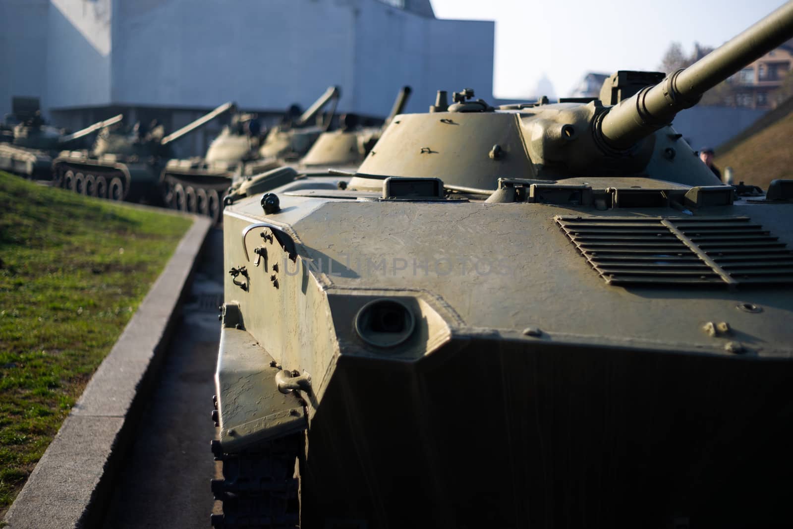 Parts of the hull of the armored infantry vehicle. In front and back of vehicle stays many different armored military vehicles. Military equipment outdoor open air museum.