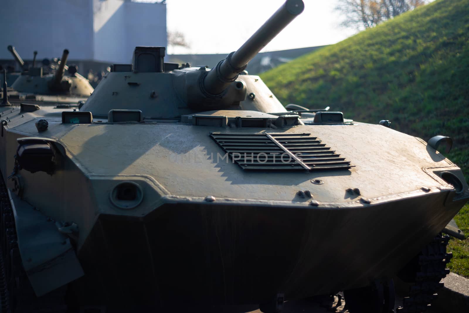 Parts of the hull of the armored infantry vehicle. In front and back of vehicle stays many different armored military vehicles. Military equipment outdoor open air museum.