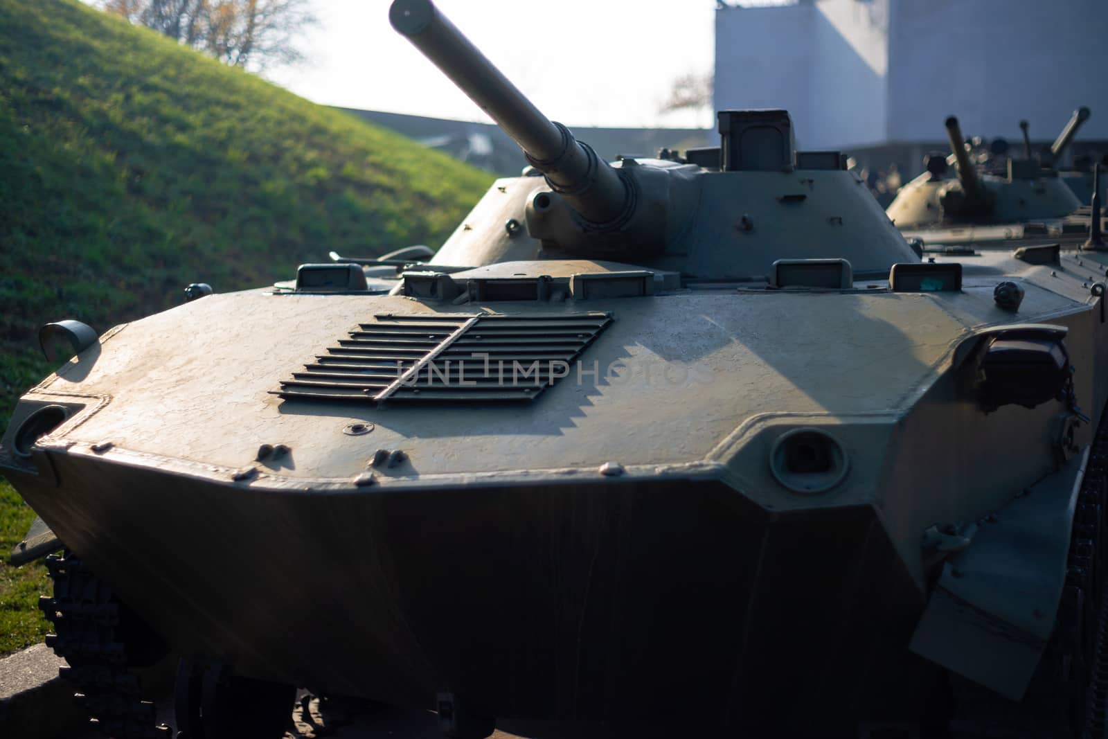 Parts of the hull of the armored infantry vehicle. In front and back of vehicle stays many different armored military vehicles. Military equipment outdoor open air museum.
