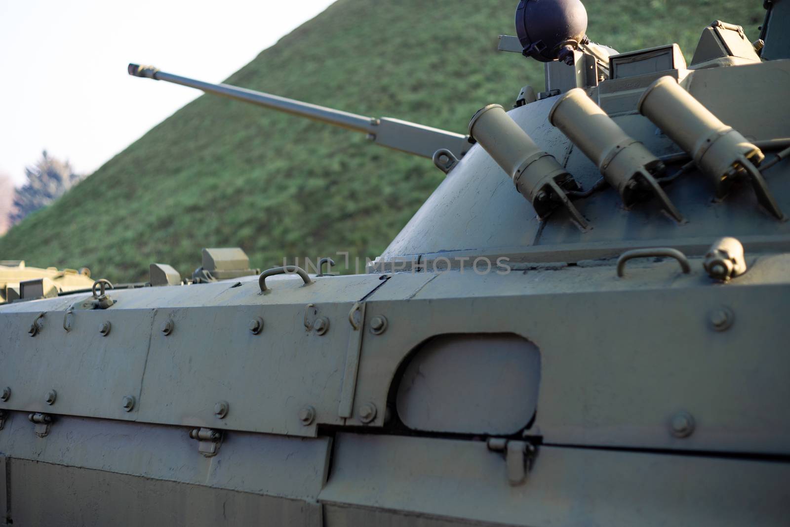 Parts of the hull of the armored infantry vehicle. In front and back of vehicle stays many different armored military vehicles. Military equipment outdoor open air museum.