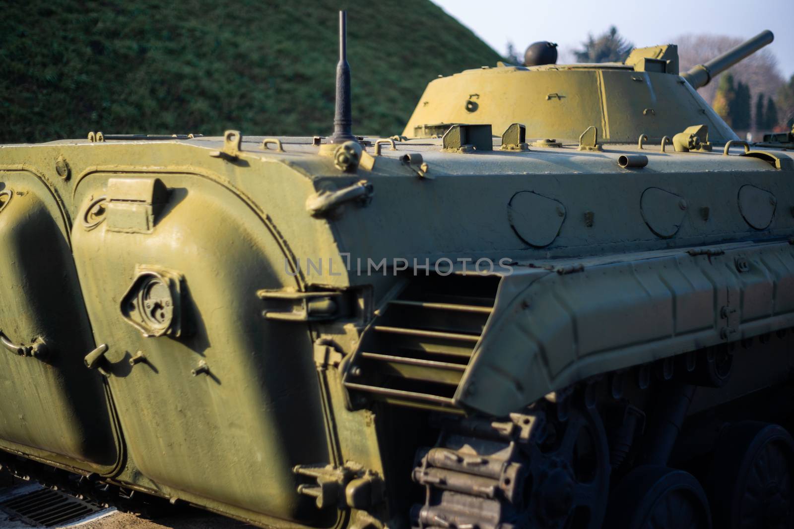 Parts of the hull of the armored infantry vehicle. In front and back of vehicle stays many different armored military vehicles. Military equipment outdoor open air museum.