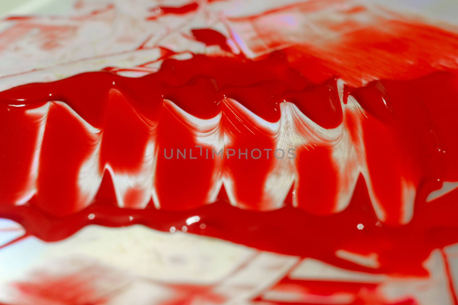 Hue red acrylic paint on glare table. Palette on table. Artist life.