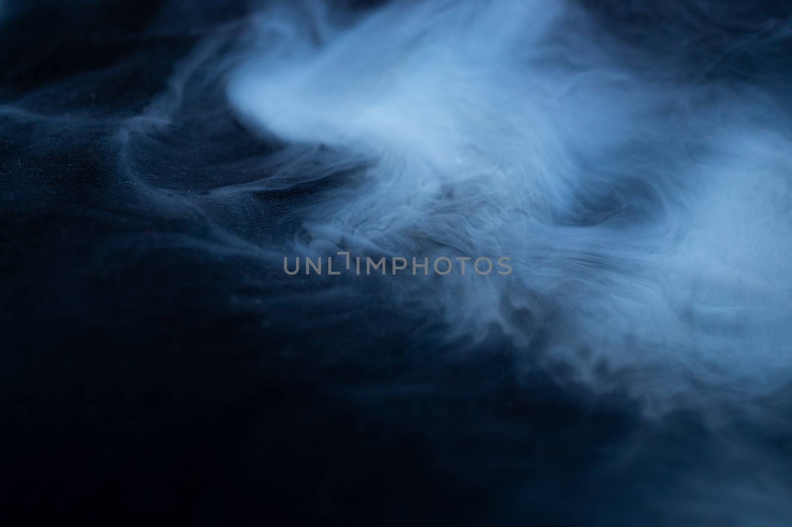 White smoke on black fabric background. Smoke spreads over the background. Vaping culture, life without cigarettes. Conceptual image.