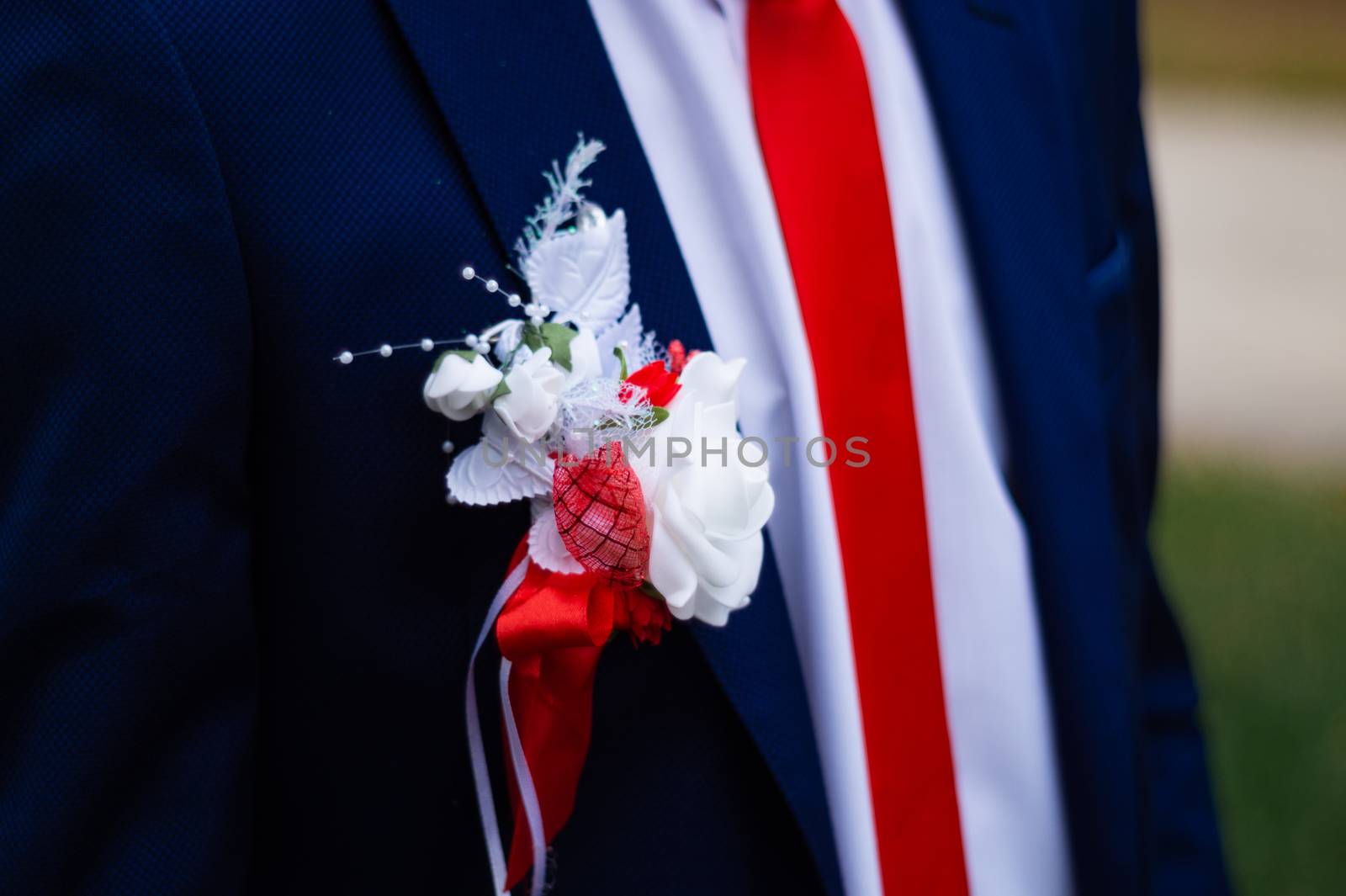 Groom's suit with a flower on his chest. Wedding details in close-up view.