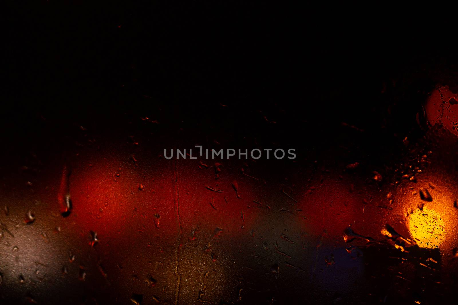 Night colorful big city lights through car windshield.

Light are defocused and blurred. Focus on windshield. Underexposed photo.