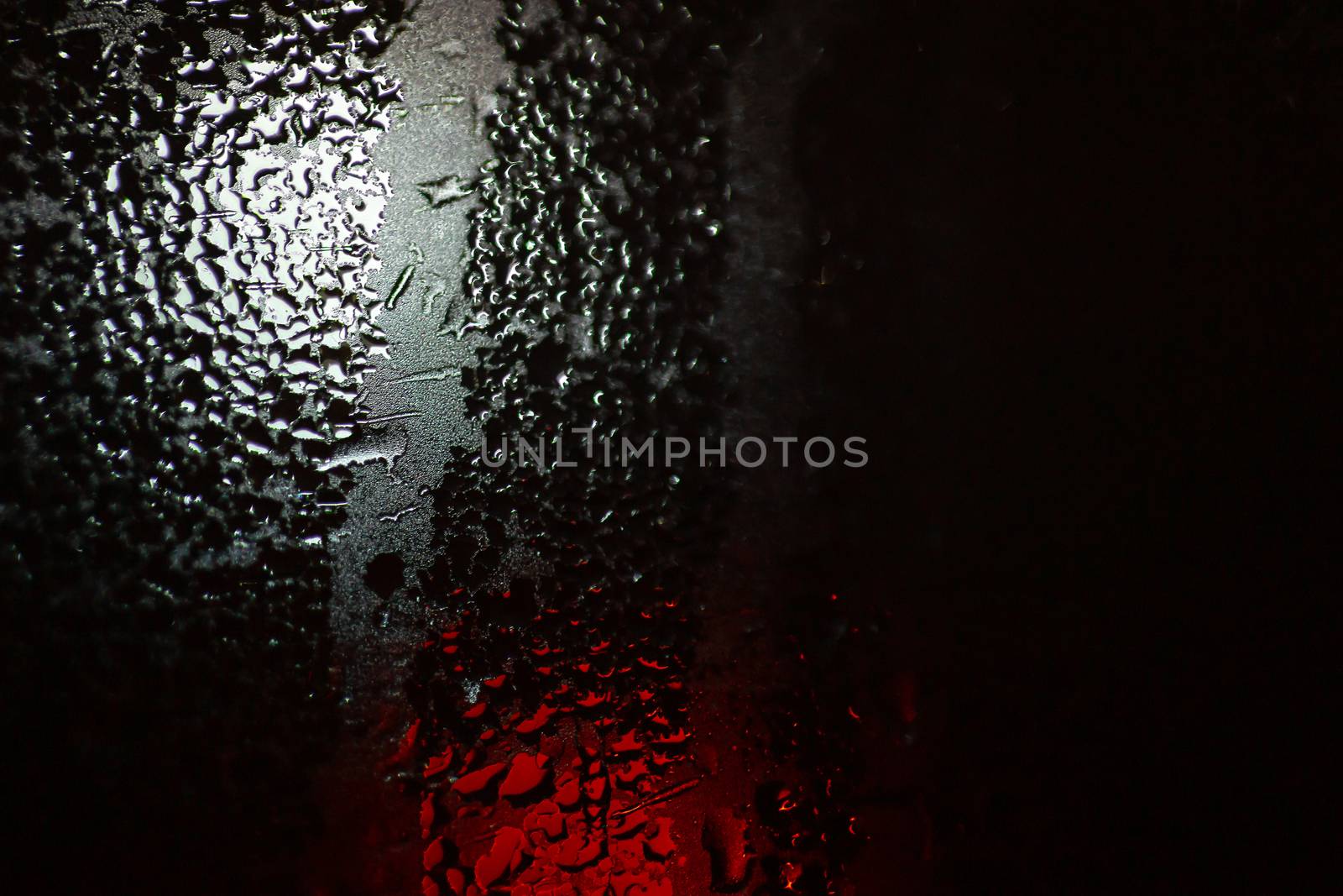 Night colorful big city lights through car windshield.

Light are defocused and blurred. Focus on windshield. Underexposed photo.