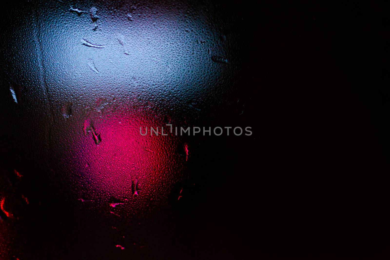 Night colorful big city lights through car windshield.

Light are defocused and blurred. Focus on windshield. Underexposed photo.